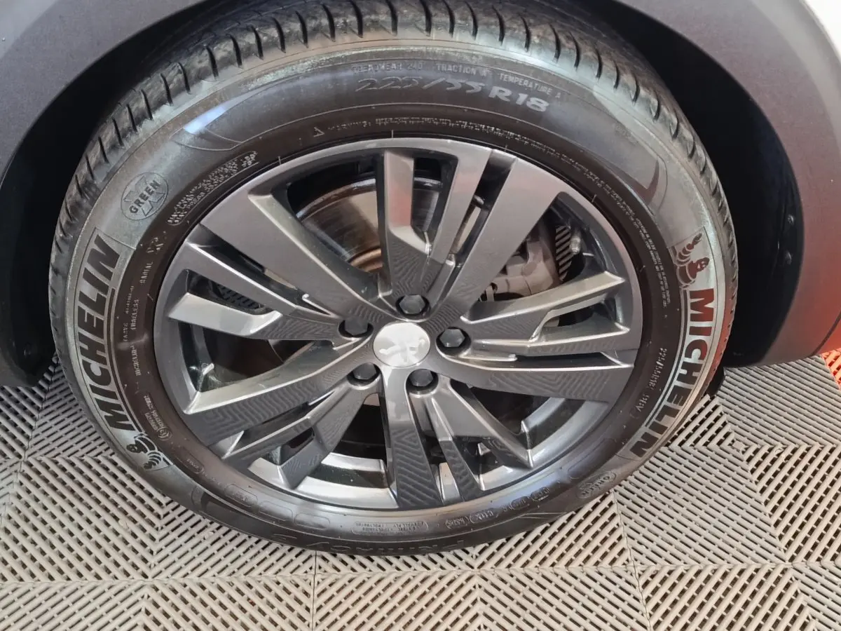 Gros plan sur la roue avant droite du Peugeot 3008 blanc, jante alliage gris foncé et pneu Michelin visible.