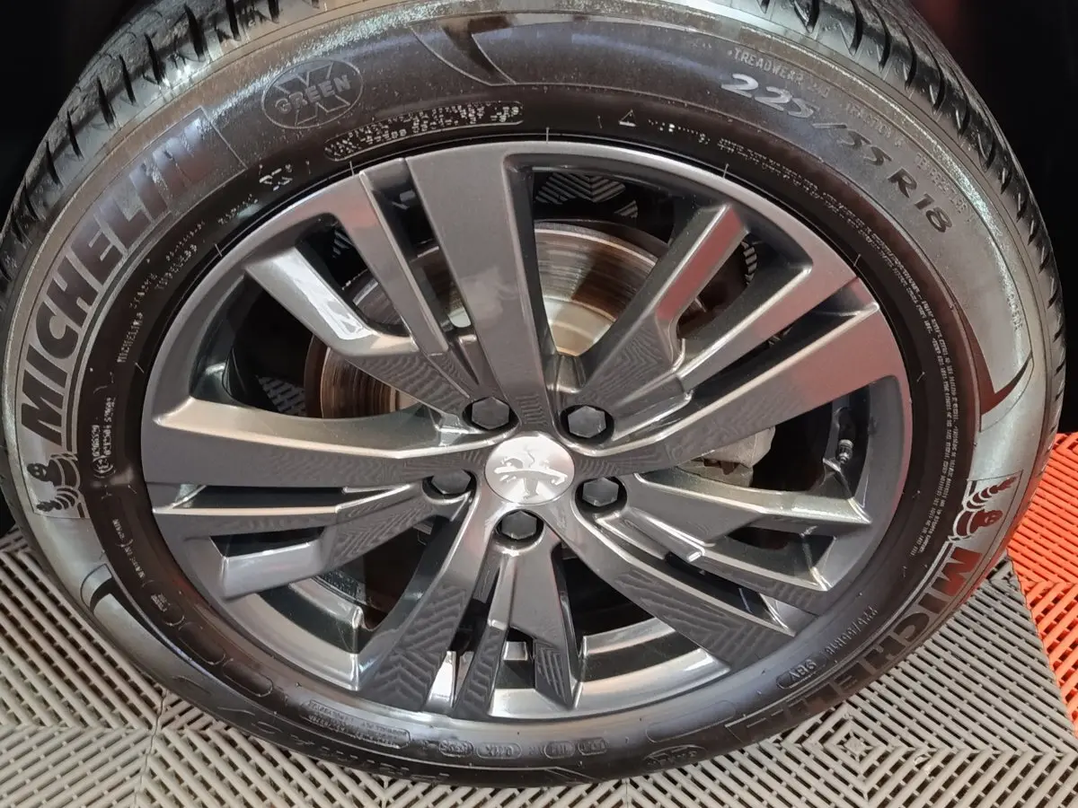 Gros plan sur la jante alliage gris foncé et pneu Michelin d’un Peugeot 3008 blanc, vue latérale droite.