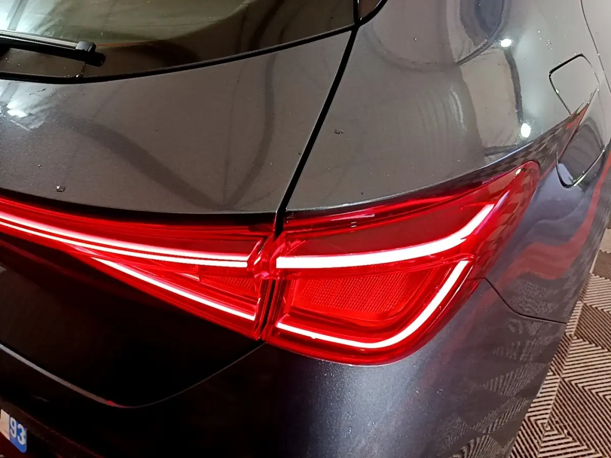Gros plan sur le feu arrière droit rouge vif d’une SEAT LEON gris clair 2023, soulignant la carrosserie lisse.