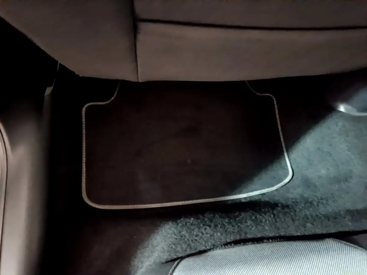 Vue rapprochée du sol côté arrière d’un SEAT Leon 2023 gris clair, montrant la moquette et tapis de sol noir.