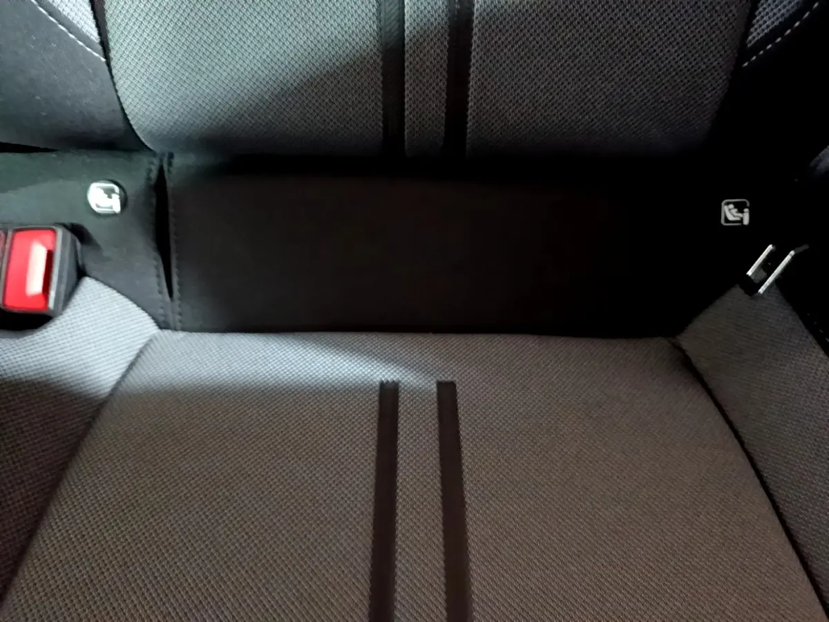 Gros plan sur la banquette arrière grise du SEAT LEON 2023 avec ceinture rouge et fixation Isofix visibles.