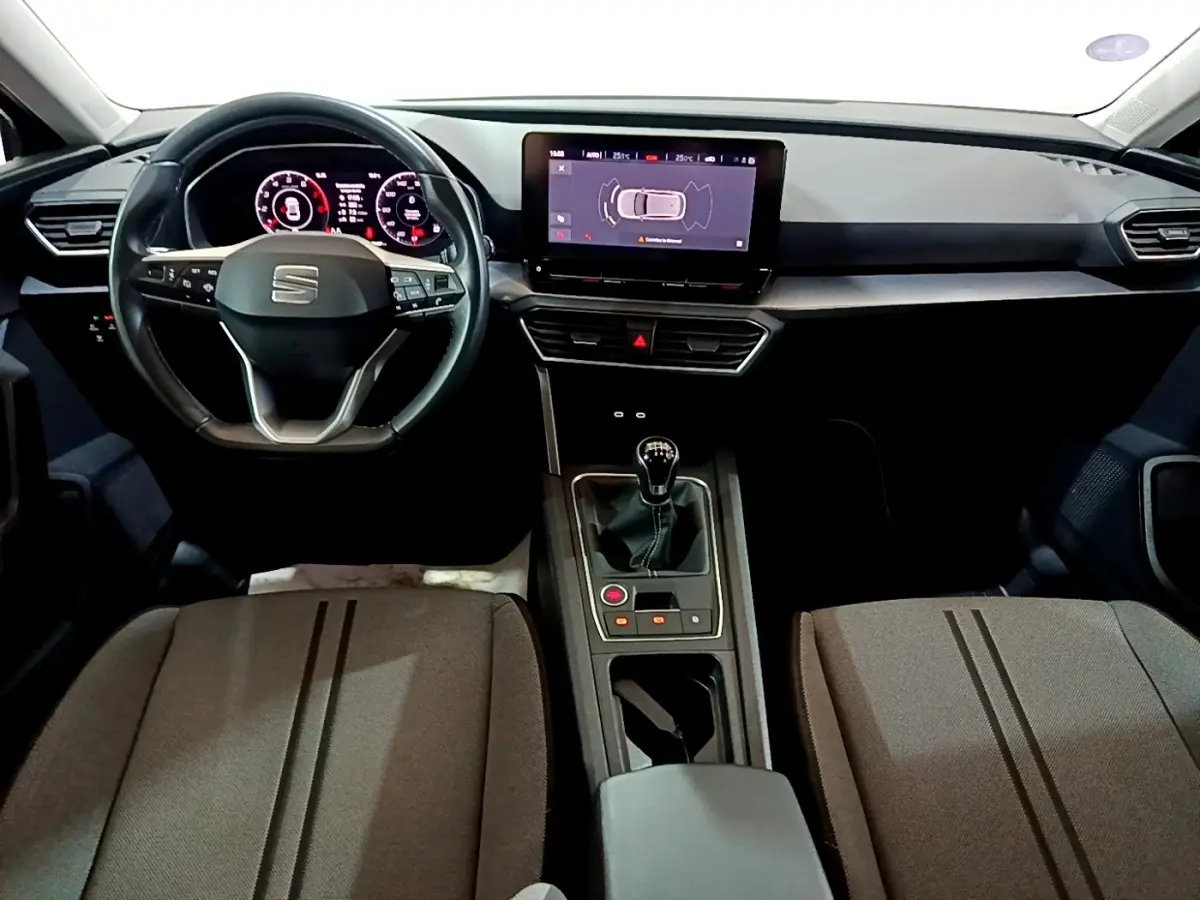 Vue intérieure avant du SEAT Leon 2023 essence gris clair, volant cuir, écran tactile 10 pouces et boîte manuelle.