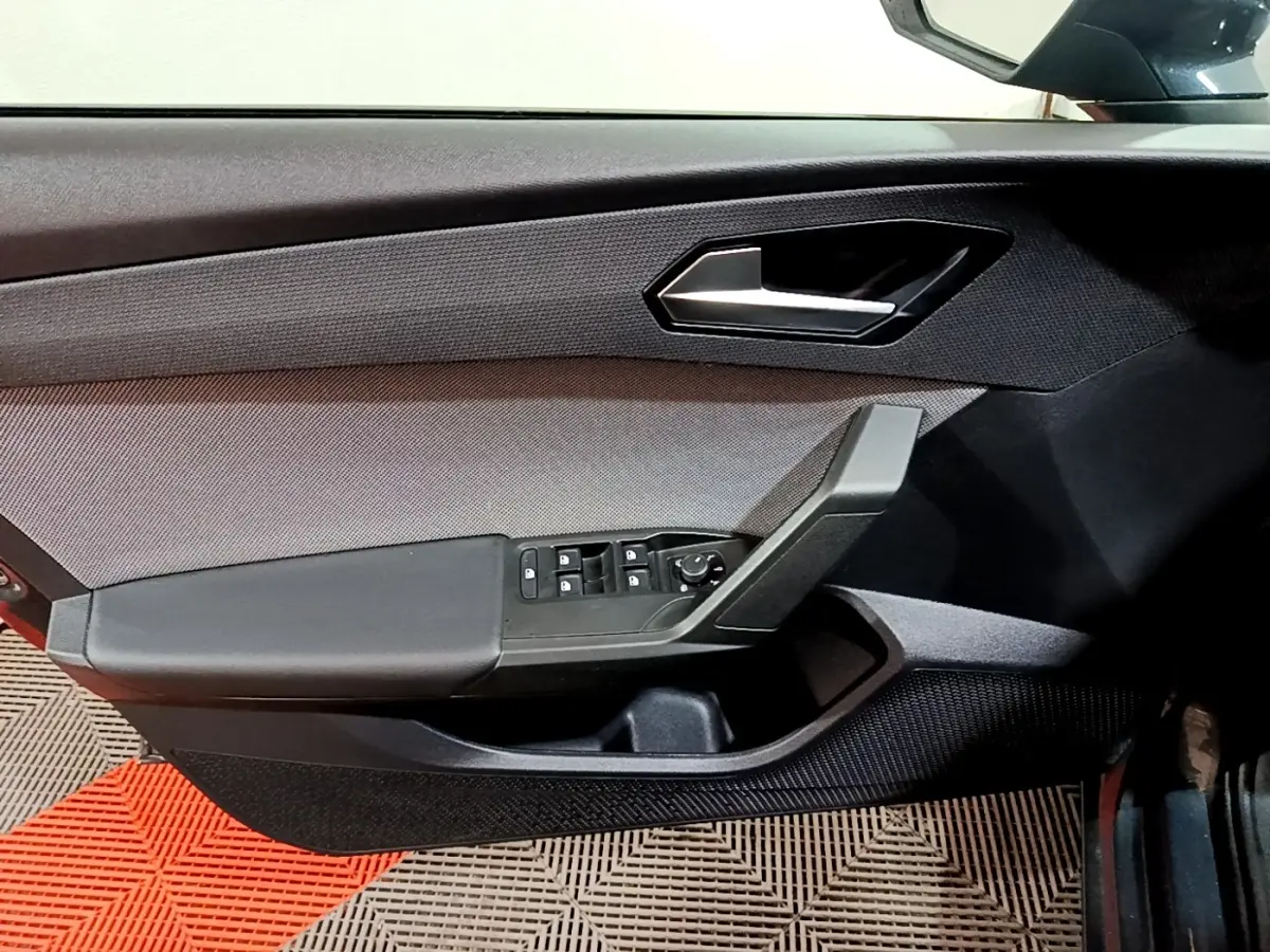 Vue intérieure du panneau de porte avant gauche gris foncé du SEAT Leon 2023 avec commandes électriques des vitres et rétroviseurs.