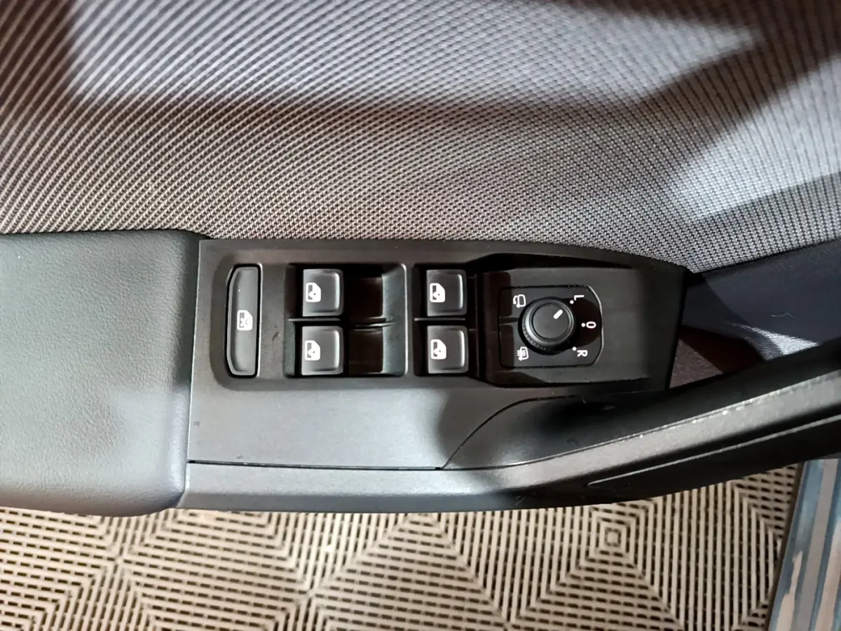 Vue rapprochée des commandes de lève-vitres et réglage des rétroviseurs sur la porte côté conducteur d'une SEAT Leon gris clair.