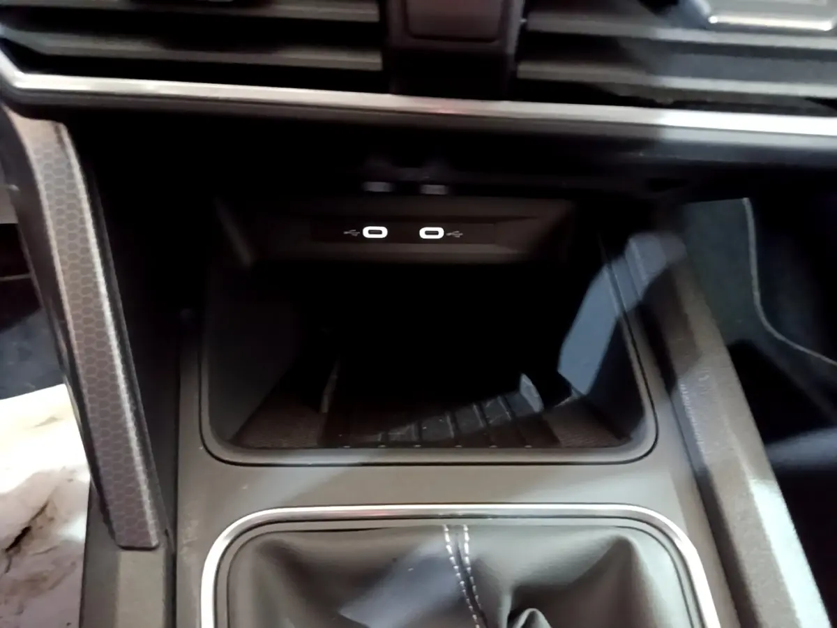 Gros plan sur la console centrale du SEAT Leon 2023, montrant la zone de recharge par induction et ports USB.