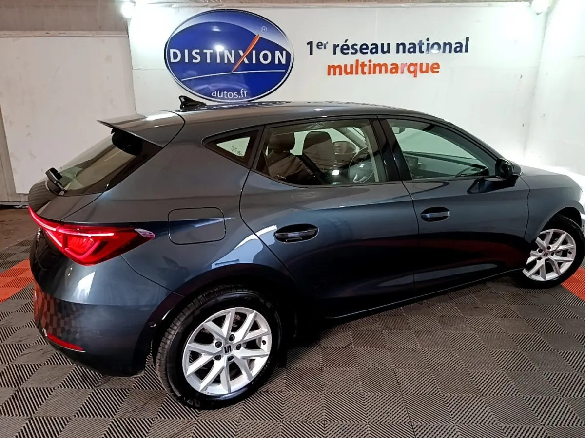 Vue côté droit arrière d'une SEAT Leon gris clair 2023 avec feux arrière LED et jantes alliage.