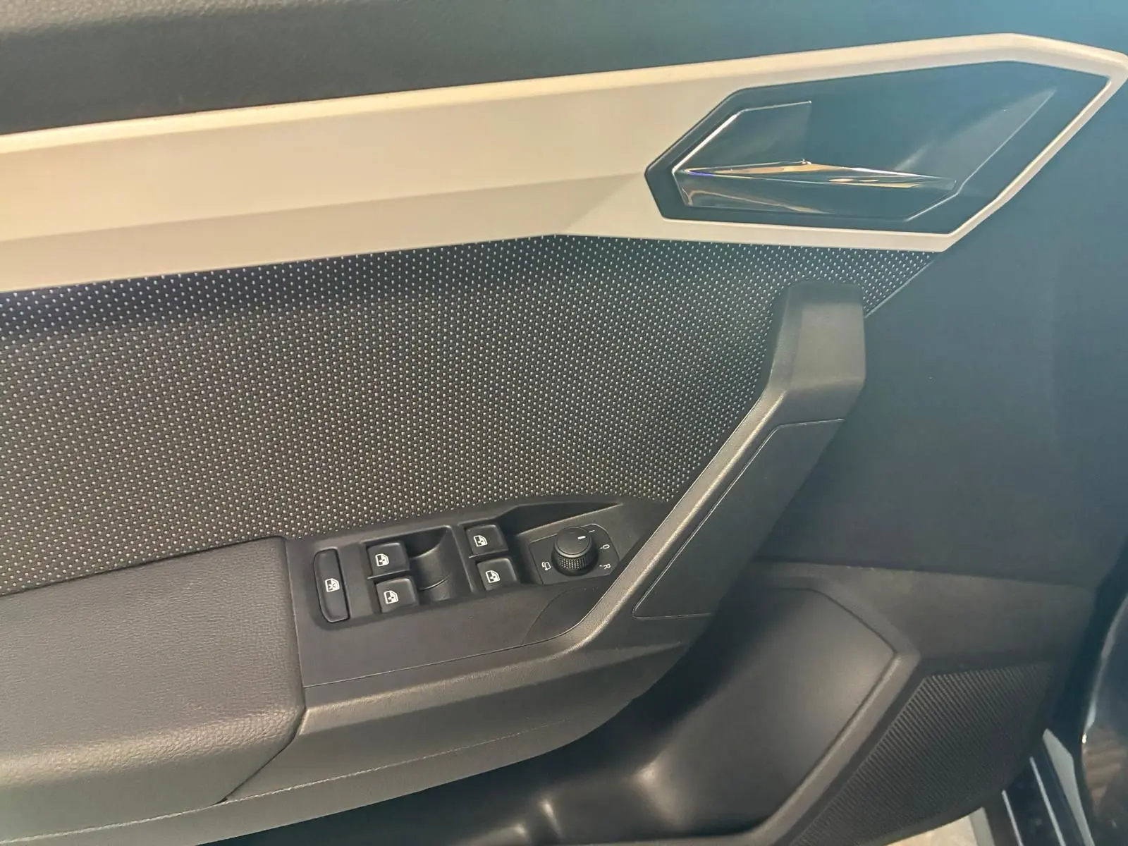 Détail de la porte avant gauche du SEAT Arona gris foncé 2021, avec commandes des vitres et poignée intérieure chromée.