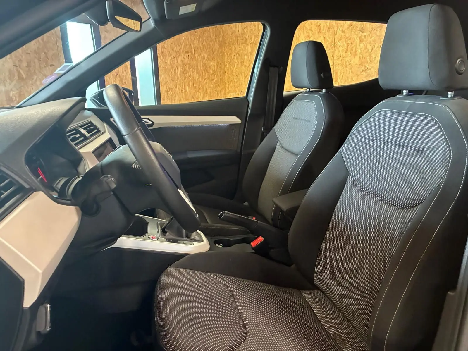 Vue intérieure côté conducteur du SEAT Arona gris foncé 2021, sièges tissu noir et tableau de bord moderne.