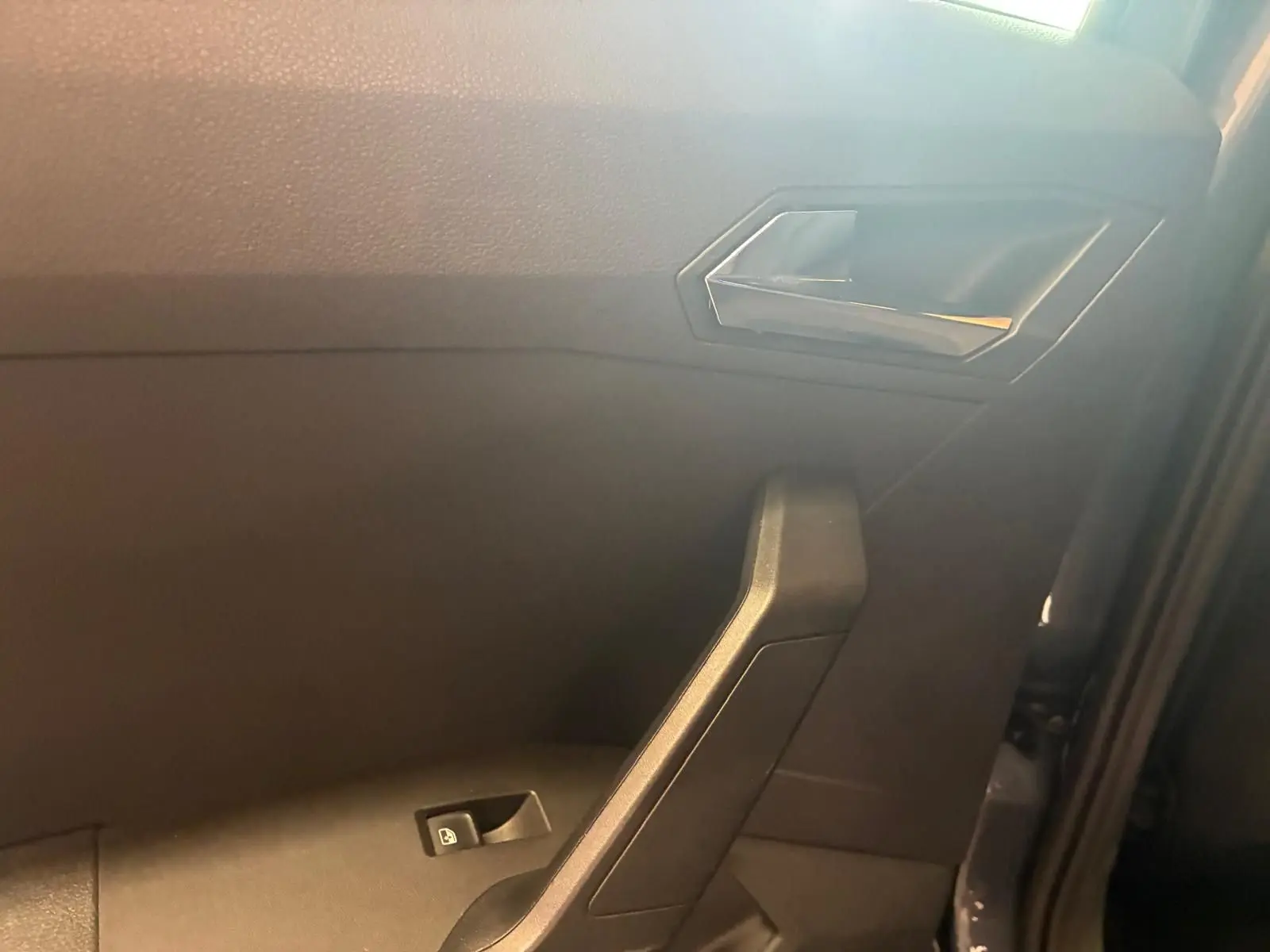 Intérieur côté gauche de la porte d’une SEAT Arona gris foncé, avec poignée et commande de vitre électrique.