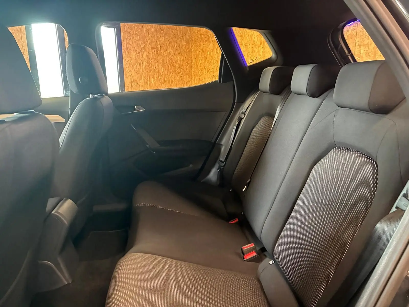 Vue intérieure côté droit des sièges arrière en tissu noir du SEAT Arona gris foncé 2021, ambiance sobre et lumineuse.