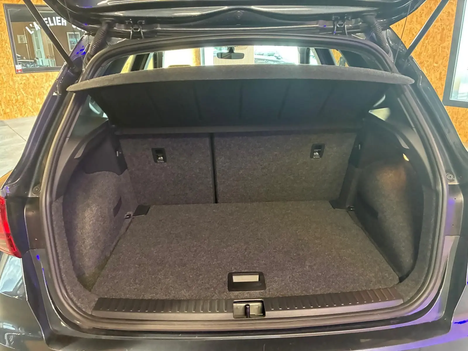 Coffre ouvert vu de l'arrière d'un SEAT Arona gris foncé, montrant un espace de chargement propre et vide.