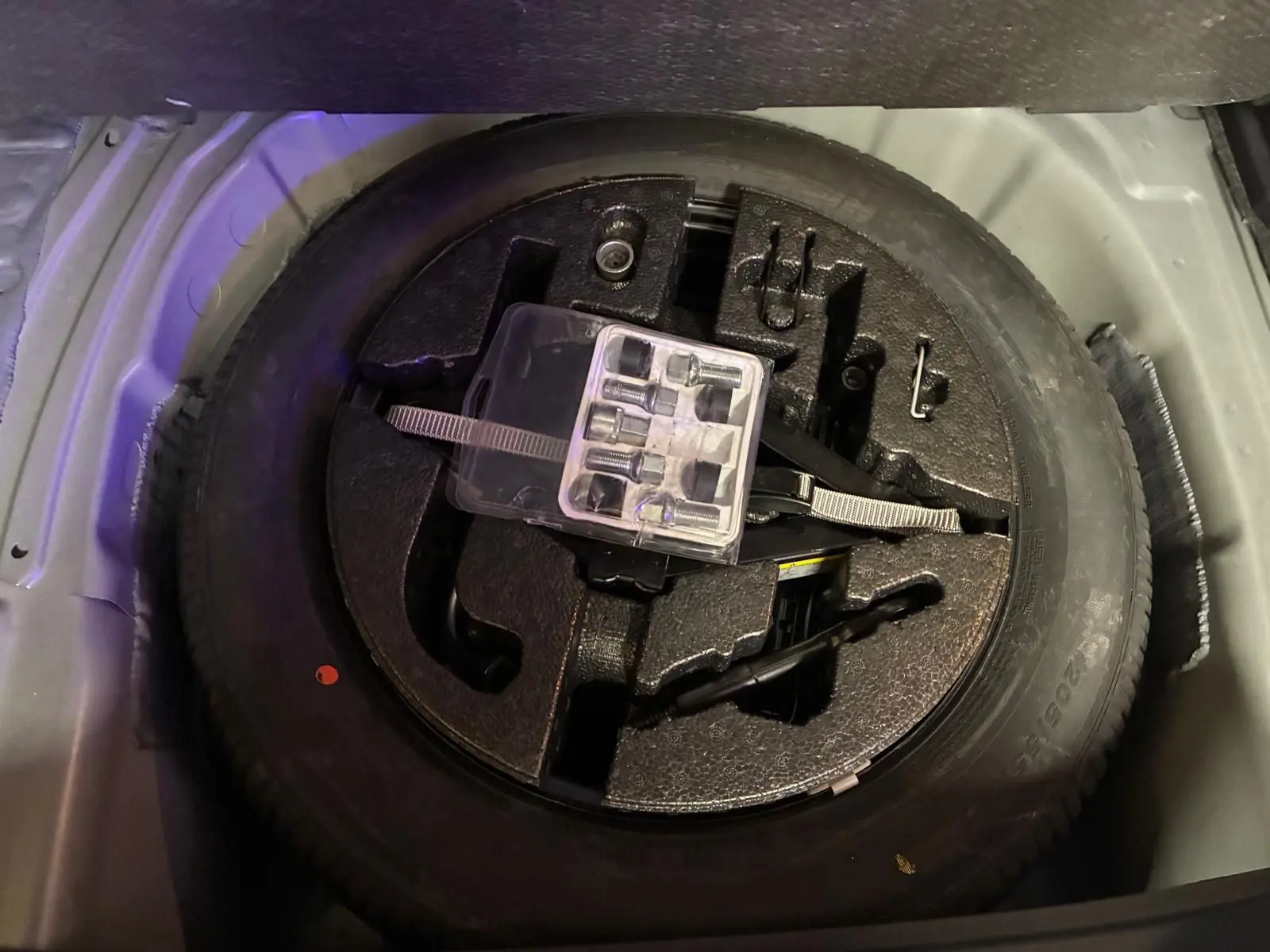 Roue de secours avec outils de changement rangés dans le coffre d'un SEAT Arona gris foncé.