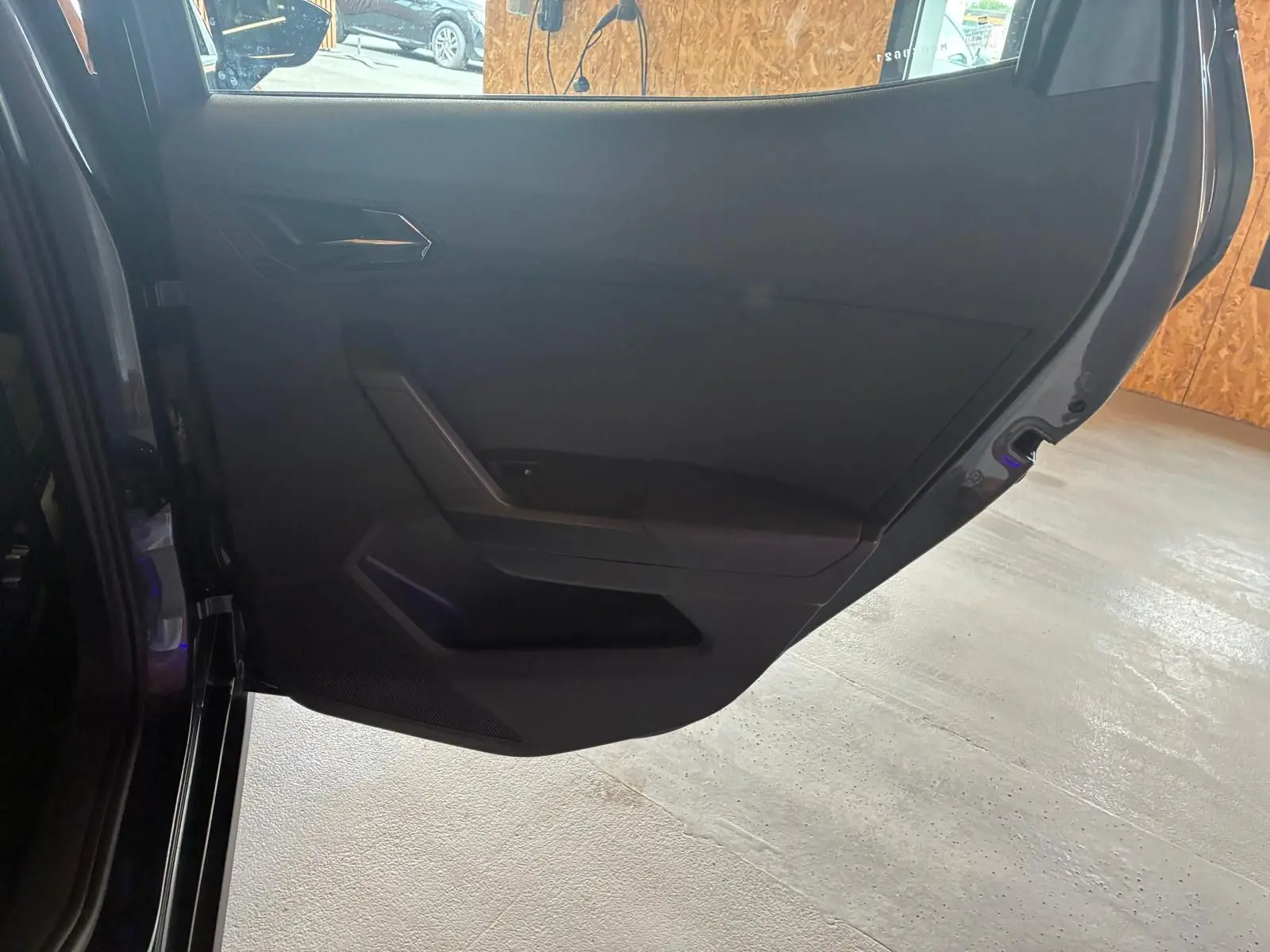 Vue intérieure de la porte arrière gauche du SEAT Arona gris foncé, avec garniture noire et poignée intégrée.