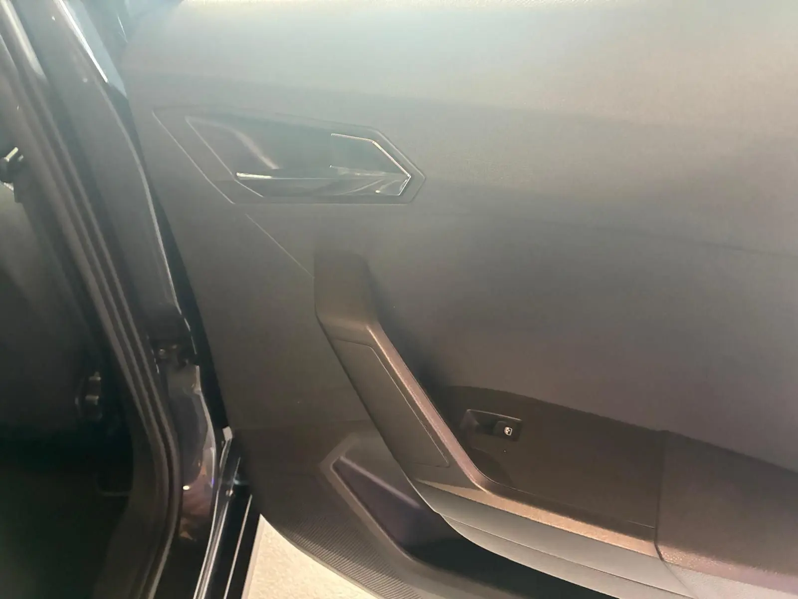 Vue intérieure côté gauche de la porte arrière d’un SEAT Arona gris foncé avec garniture noire et poignée angulaire.
