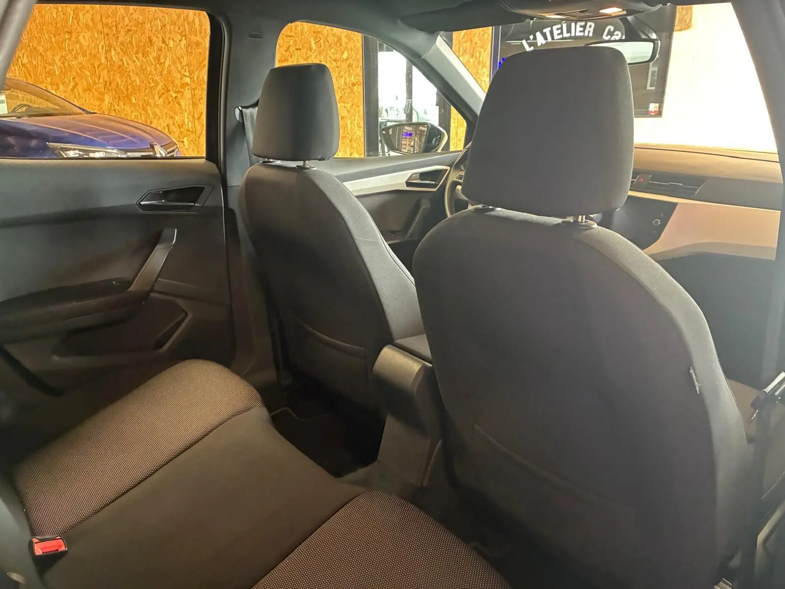 Vue intérieure arrière du SEAT Arona gris foncé, montrant les sièges en tissu noir et la planche de bord côté passager.