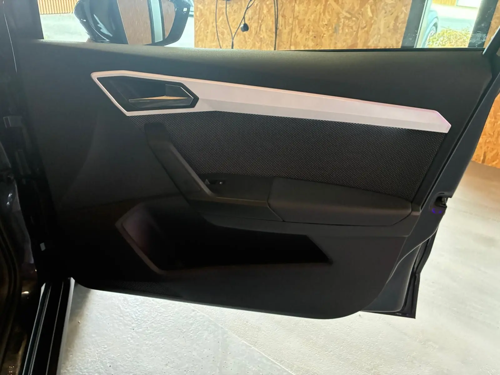 Vue intérieure de la porte avant gauche du SEAT Arona gris foncé, avec garniture noire et insert argenté.