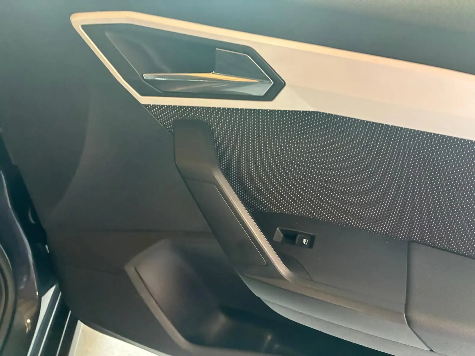 Détail de la porte intérieure côté conducteur du SEAT Arona gris foncé, avec poignée et bouton de commande de vitre.