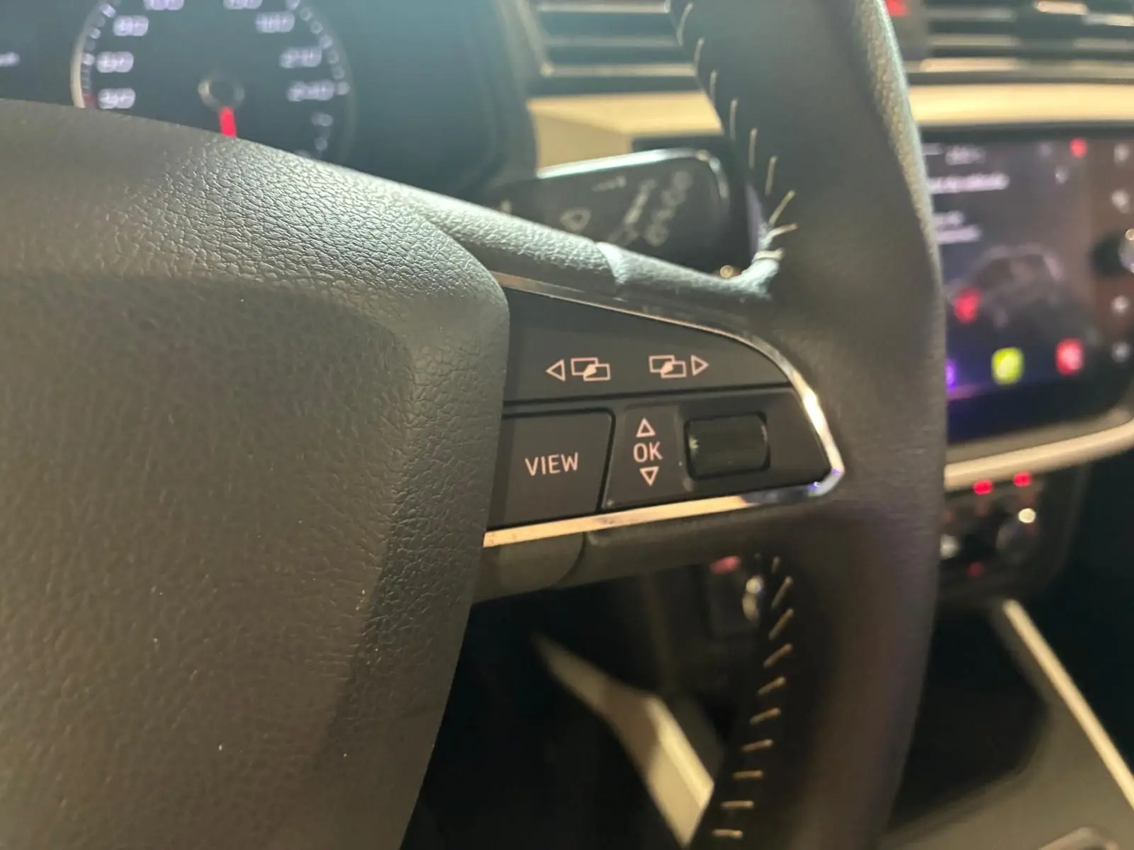 Gros plan sur les commandes gauche du volant noir du SEAT Arona 2021, avec boutons de navigation et affichage.