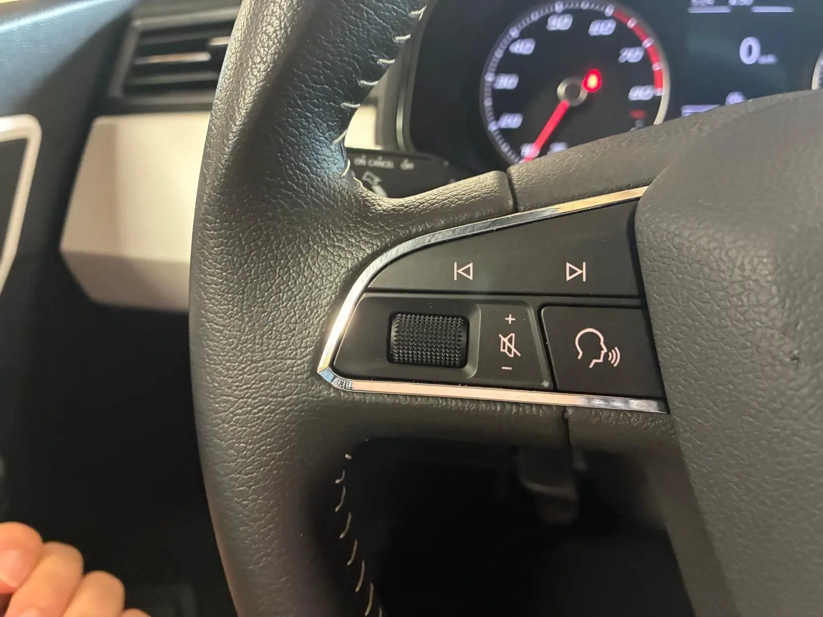 Gros plan sur les commandes audio au volant du SEAT Arona 1.0 TSI 110 Xcellence, intérieur noir avec tableau de bord visible.