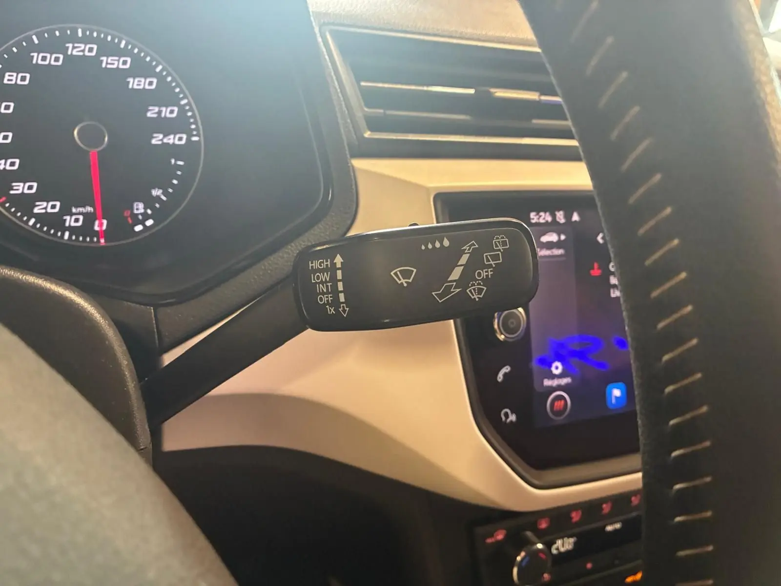 Gros plan sur la manette d’essuie-glace à gauche du volant dans l’habitacle noir du SEAT Arona gris foncé.