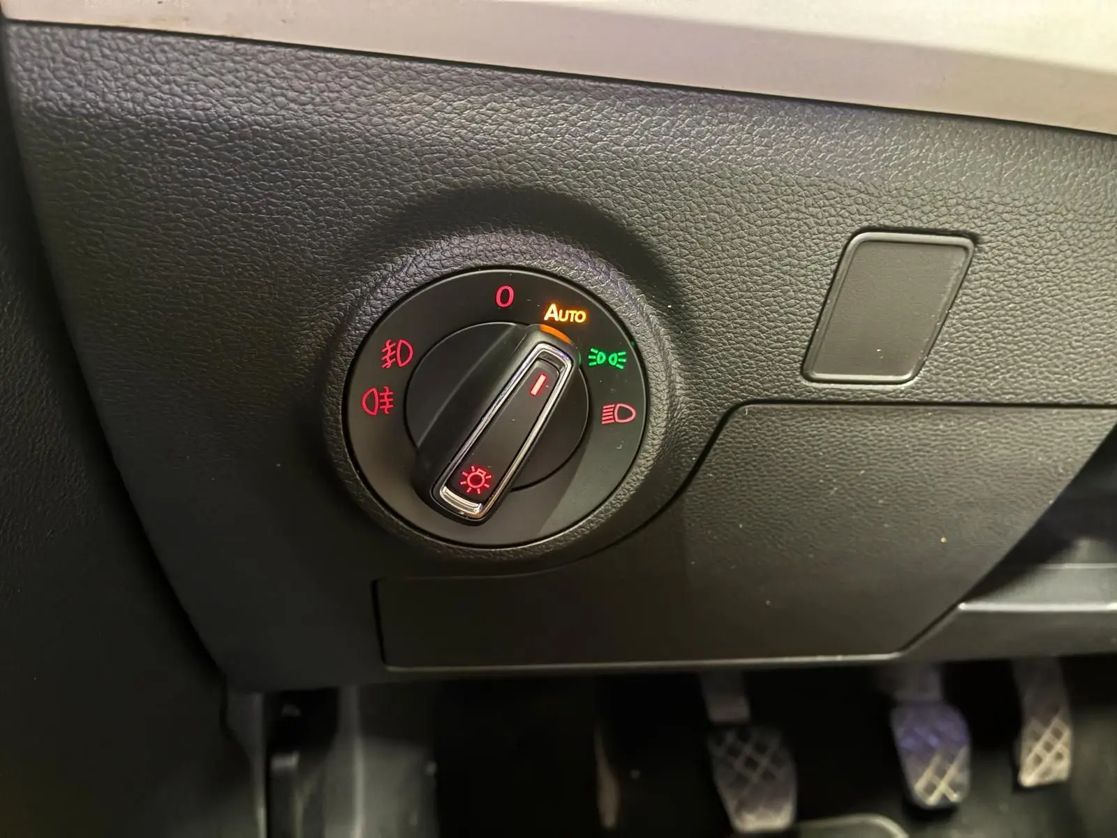 Gros plan sur le bouton de commande des phares du tableau de bord noir du SEAT Arona gris foncé, version 1.0 TSI 110 XCELLENCE.