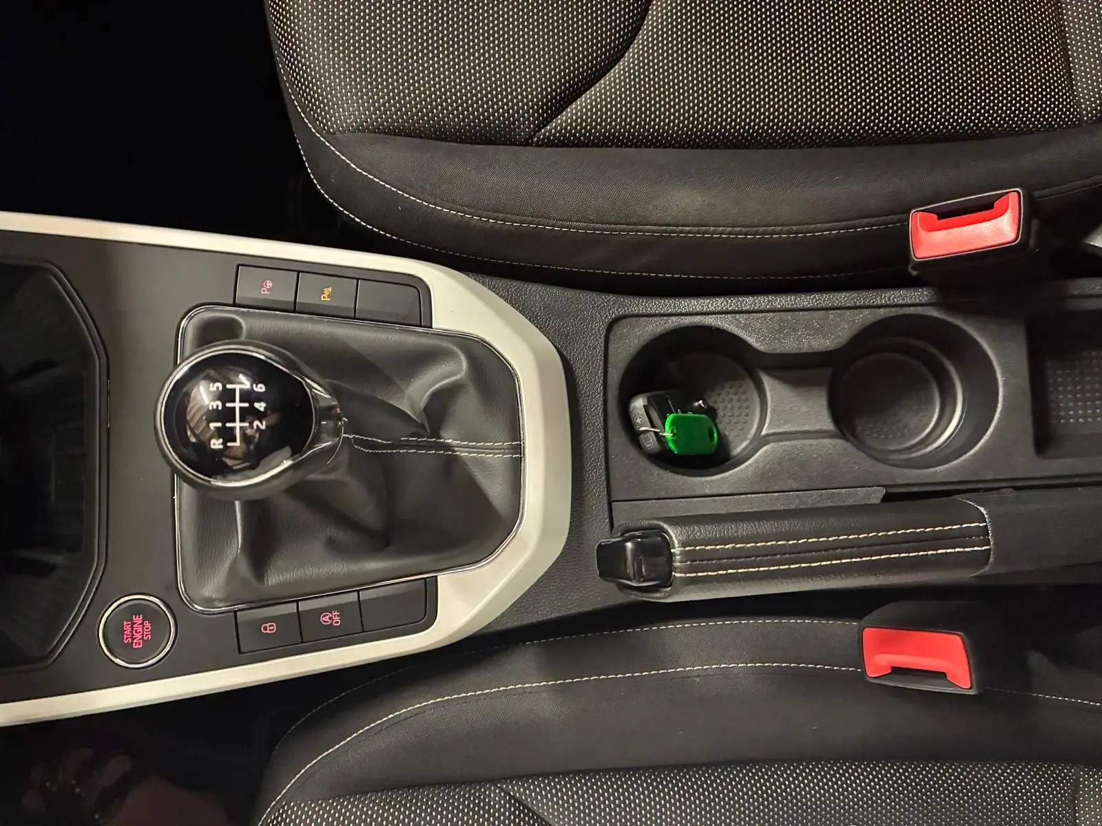 Vue rapprochée de la console centrale du SEAT Arona gris foncé, montrant le levier de vitesse manuel et les sièges en tissu noir.