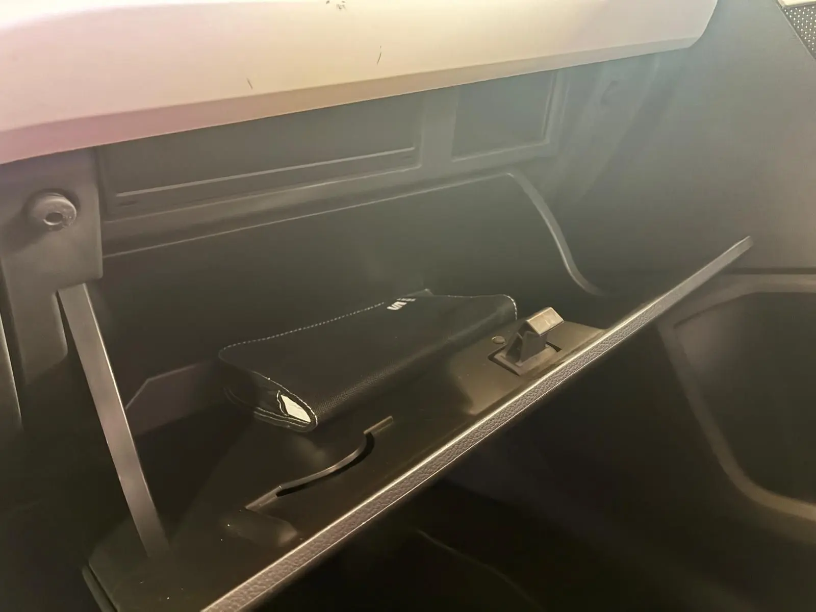 Gros plan de la boîte à gants ouverte du SEAT Arona 1.0 TSI 110 Xcellence, intérieur noir avec pochette visible.