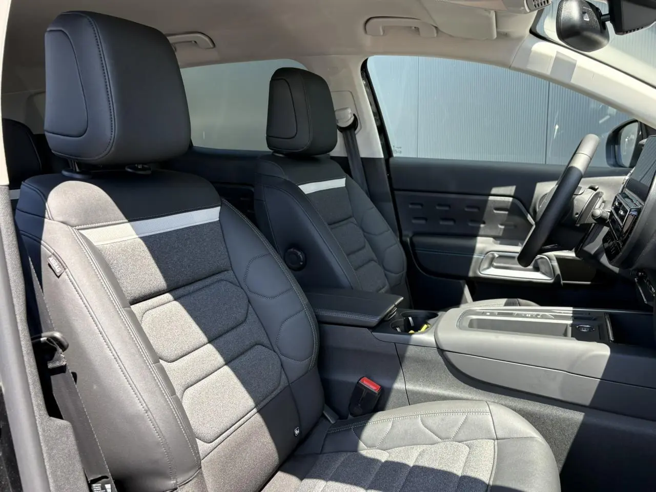 Vue intérieure côté conducteur du Citroën C5 Aircross Hybrid 2025, sièges tissu noir et gris avec surpiqûres.