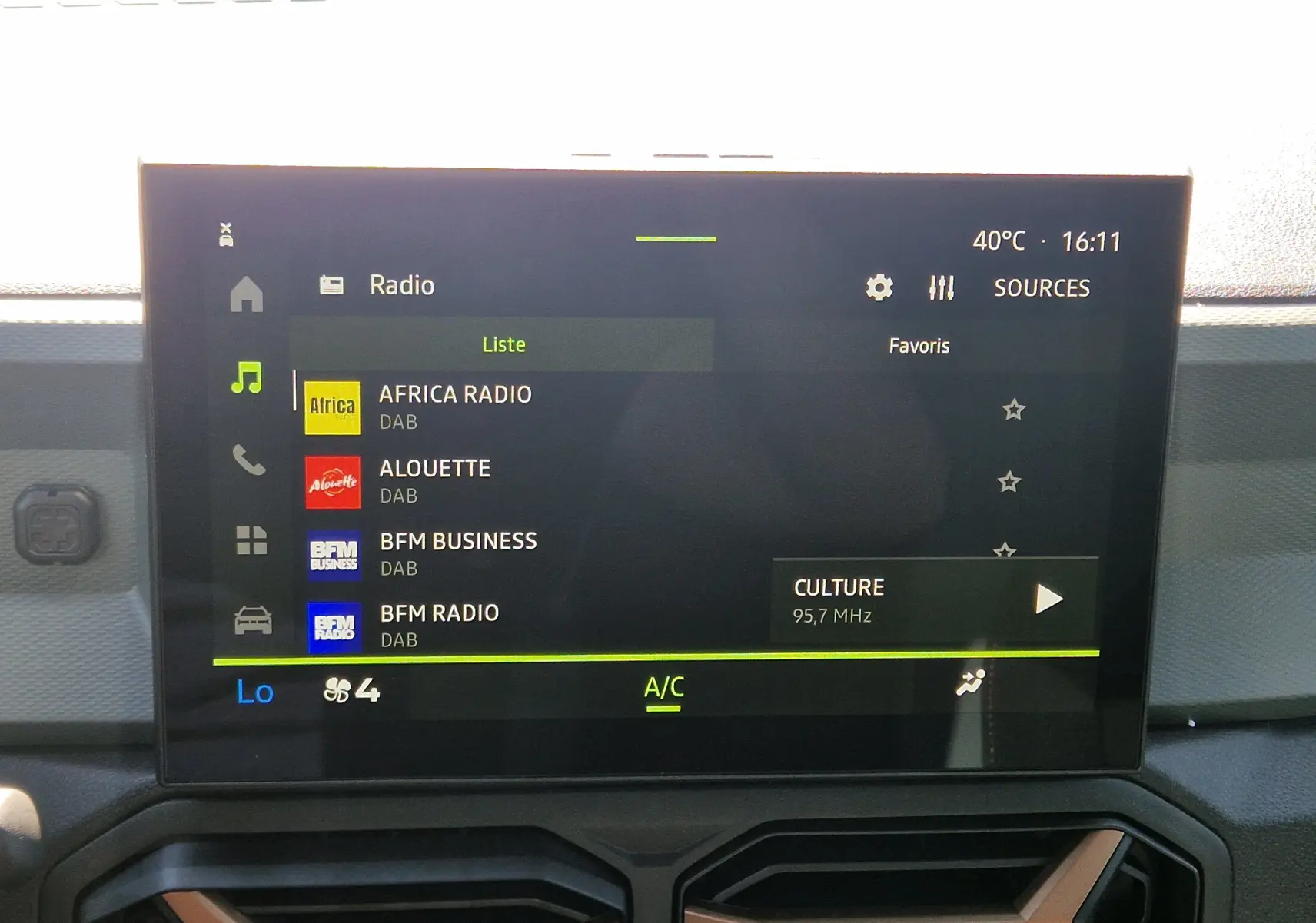 Écran tactile central du tableau de bord du Dacia Duster 2026 affichant les stations radio DAB, avec commandes climatisation visibles.