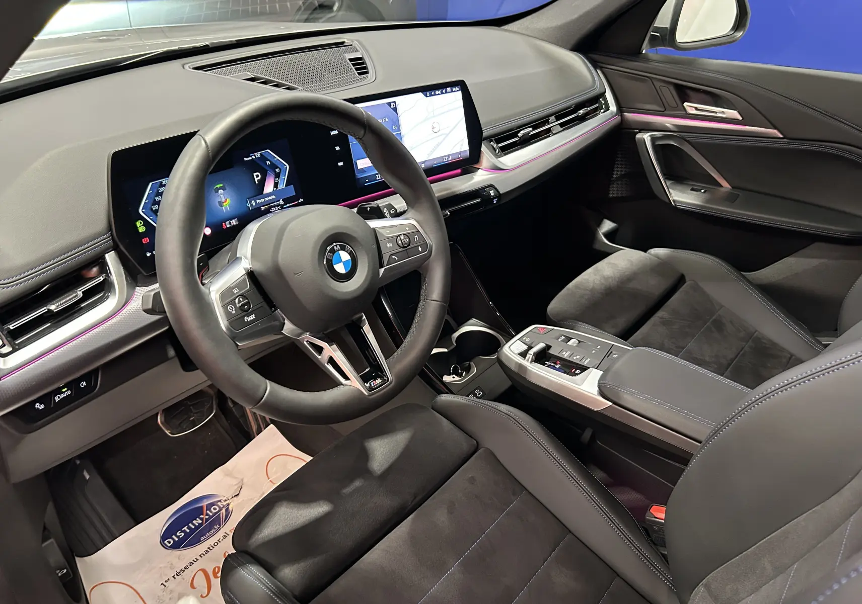 Intérieur avant droit du BMW X1 2024 M Sport avec volant cuir, tableau de bord numérique et sièges sport noirs.