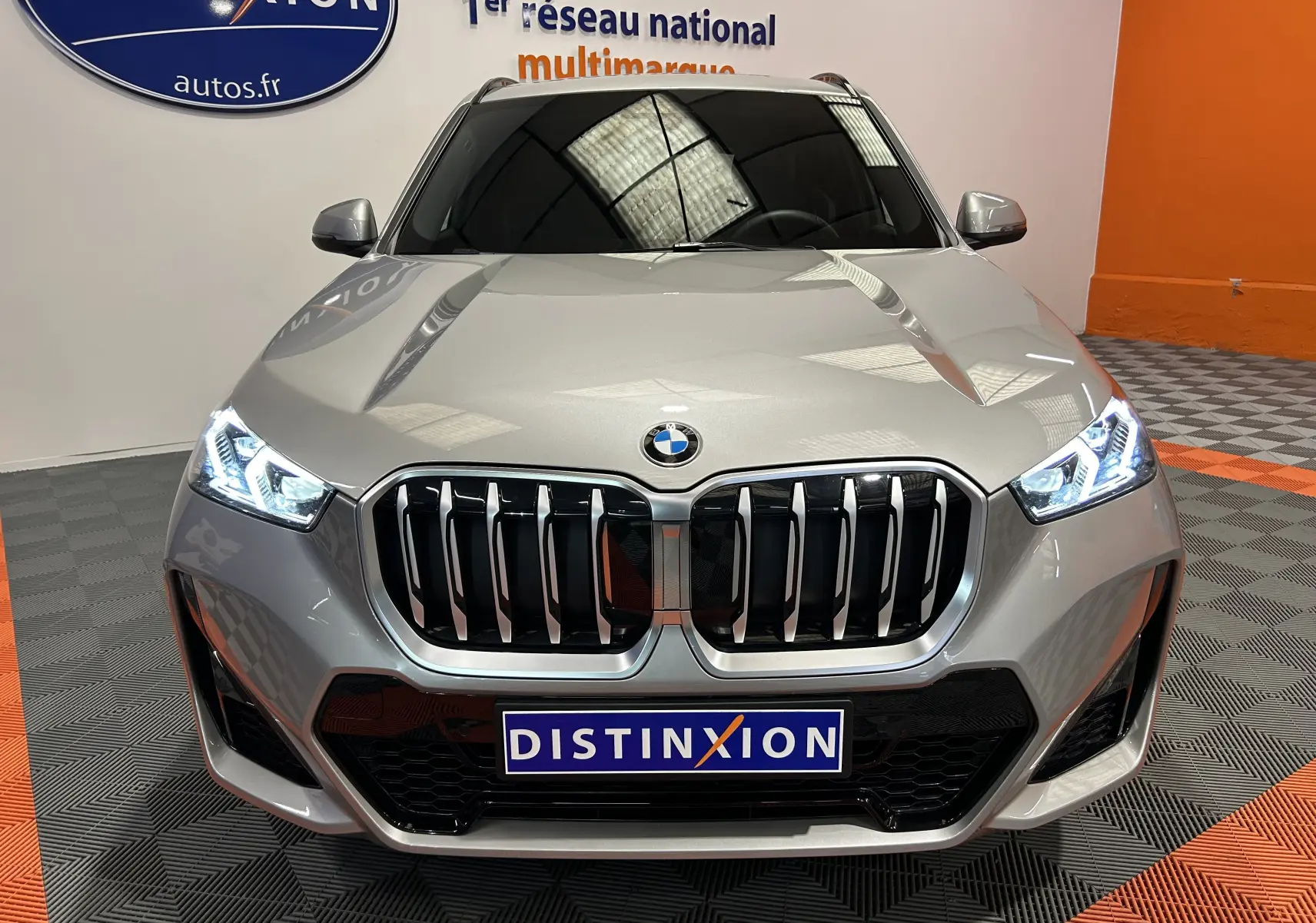 Vue frontale d'un BMW X1 sDrive20d M Sport 2024 en couleur Spacesilber avec phares LED allumés et calandre imposante.