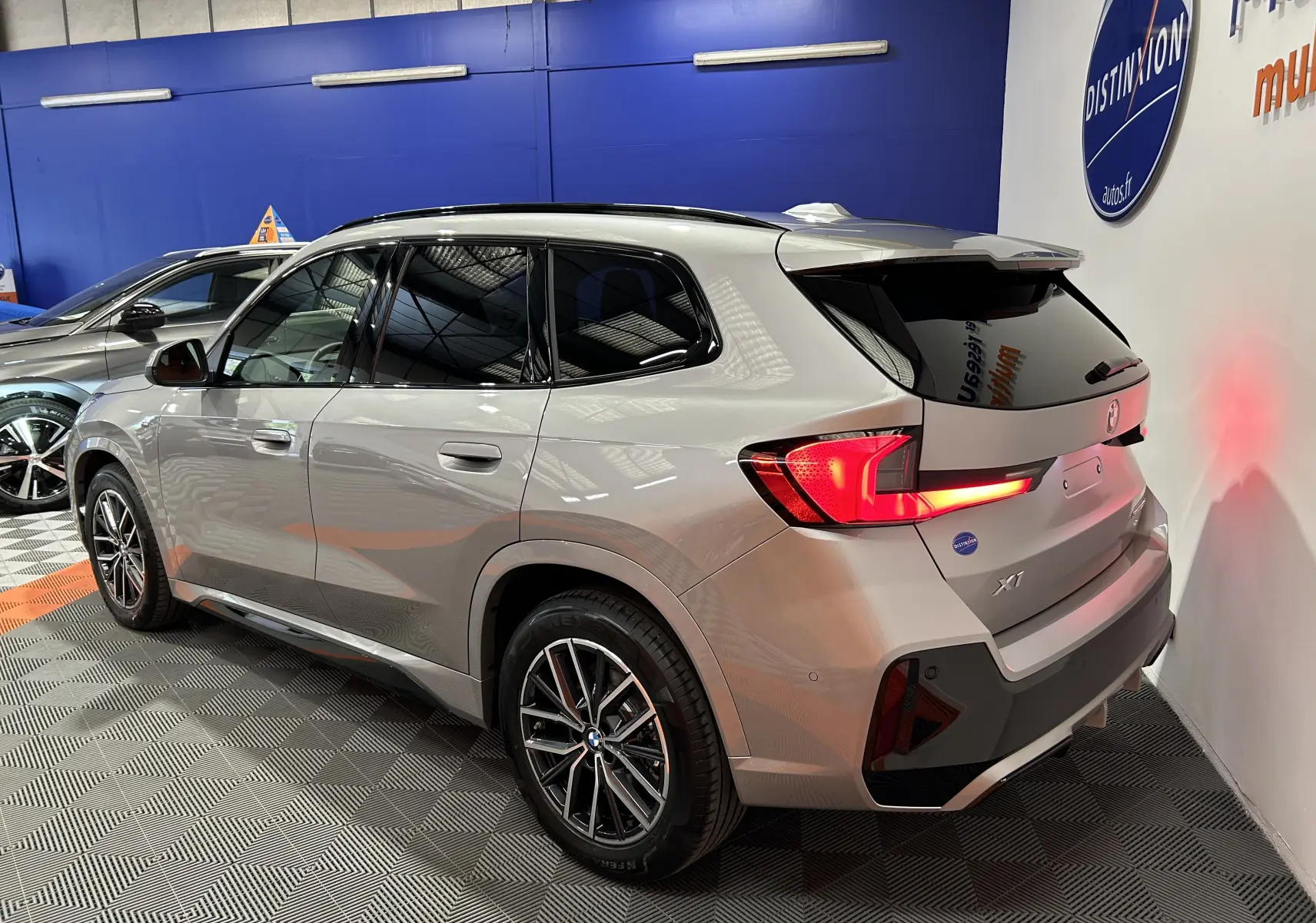 BMW X1 sDrive20d M Sport 2024 en Spacesilber, vue 3/4 arrière droit avec feux LED allumés et jantes sport.