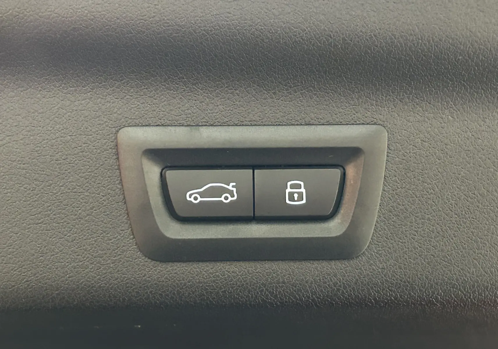 Boutons de commande pour ouverture du hayon et verrouillage, intégrés dans l'intérieur noir du BMW X1 Spacesilber 2024.