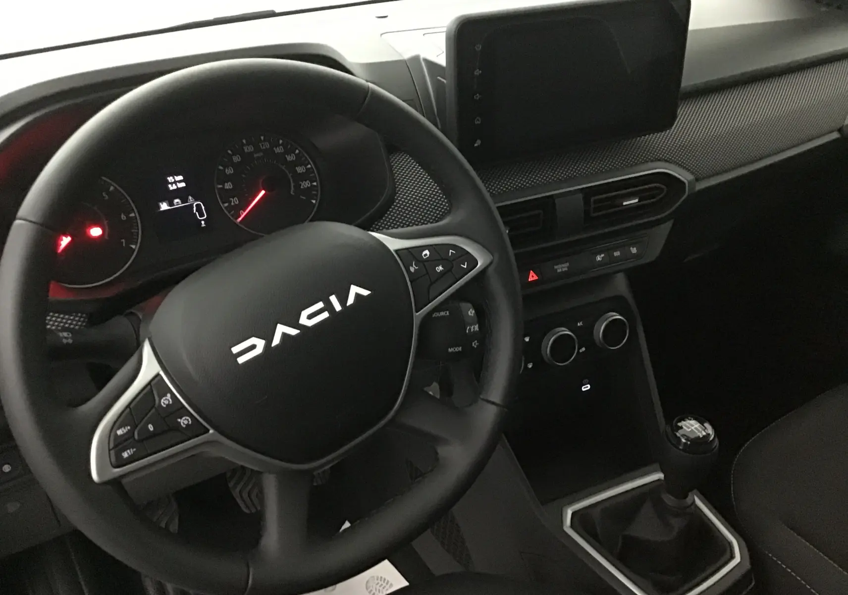 Vue intérieure centrée sur le volant et la console centrale d'une Dacia Sandero Stepway 2025 avec boîte manuelle.