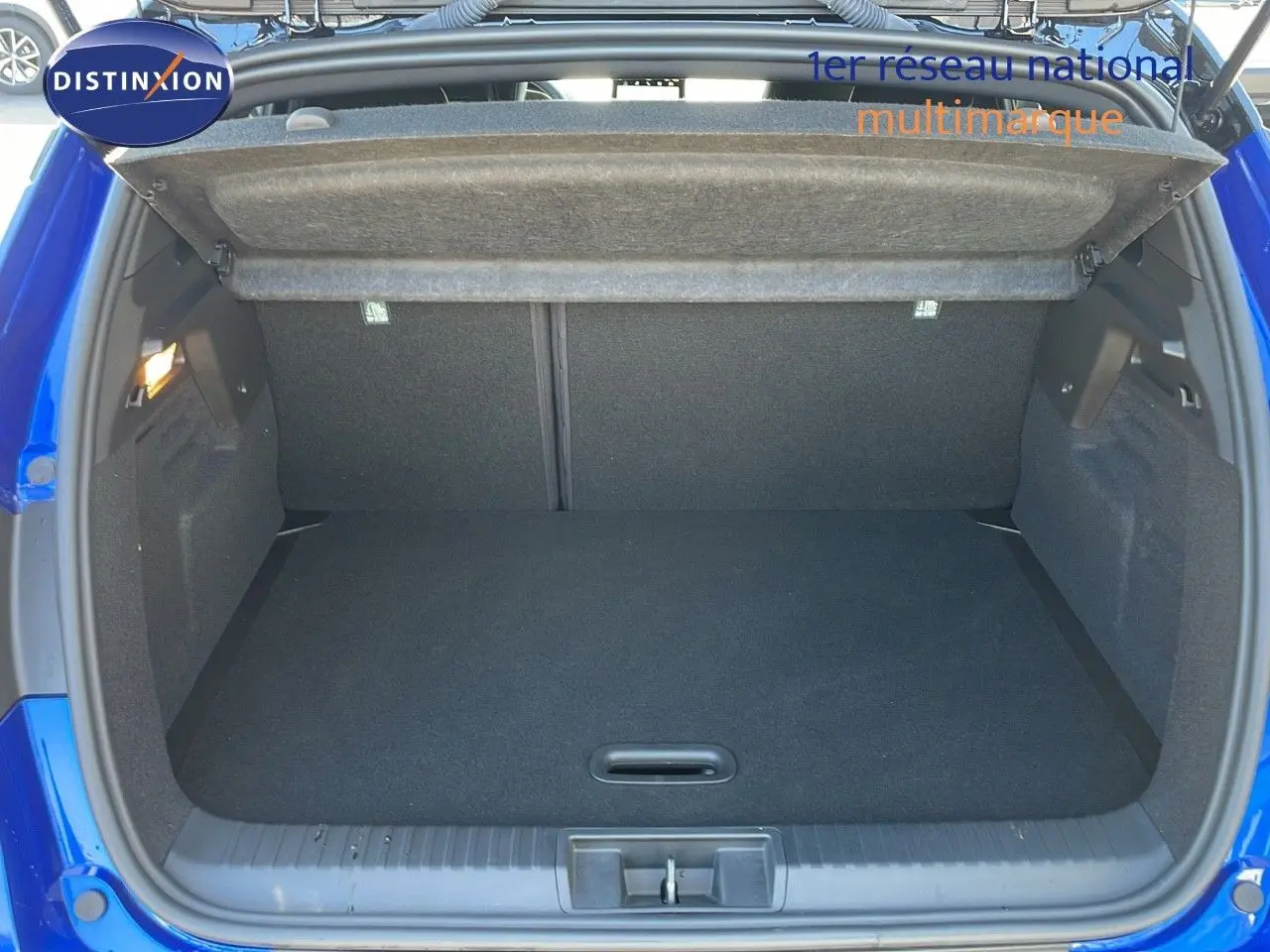 Coffre ouvert d'un Renault Captur E-Tech hybride 2025 bleu Iron Metal avec toit noir, vue arrière intérieure.
