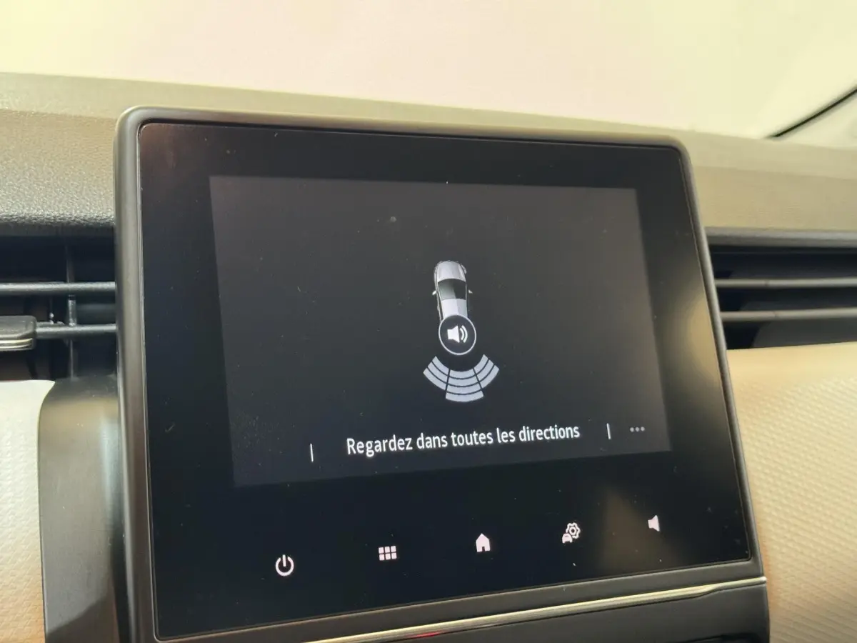 Écran tactile intérieur de la Renault Clio Business blanc, affichant l'alerte de détection d'obstacles au stationnement.