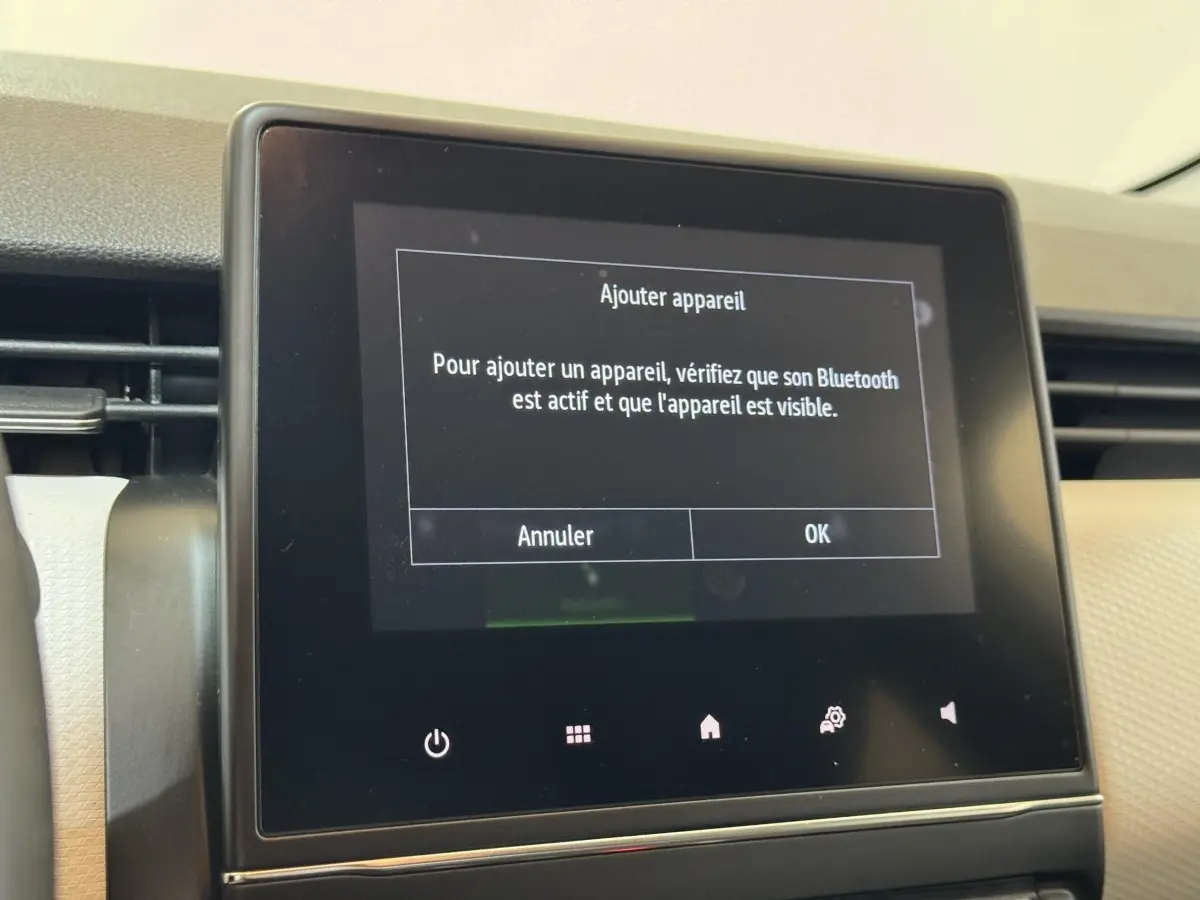 Écran tactile central du tableau de bord de la Renault Clio Business blanc, affichant un message Bluetooth.