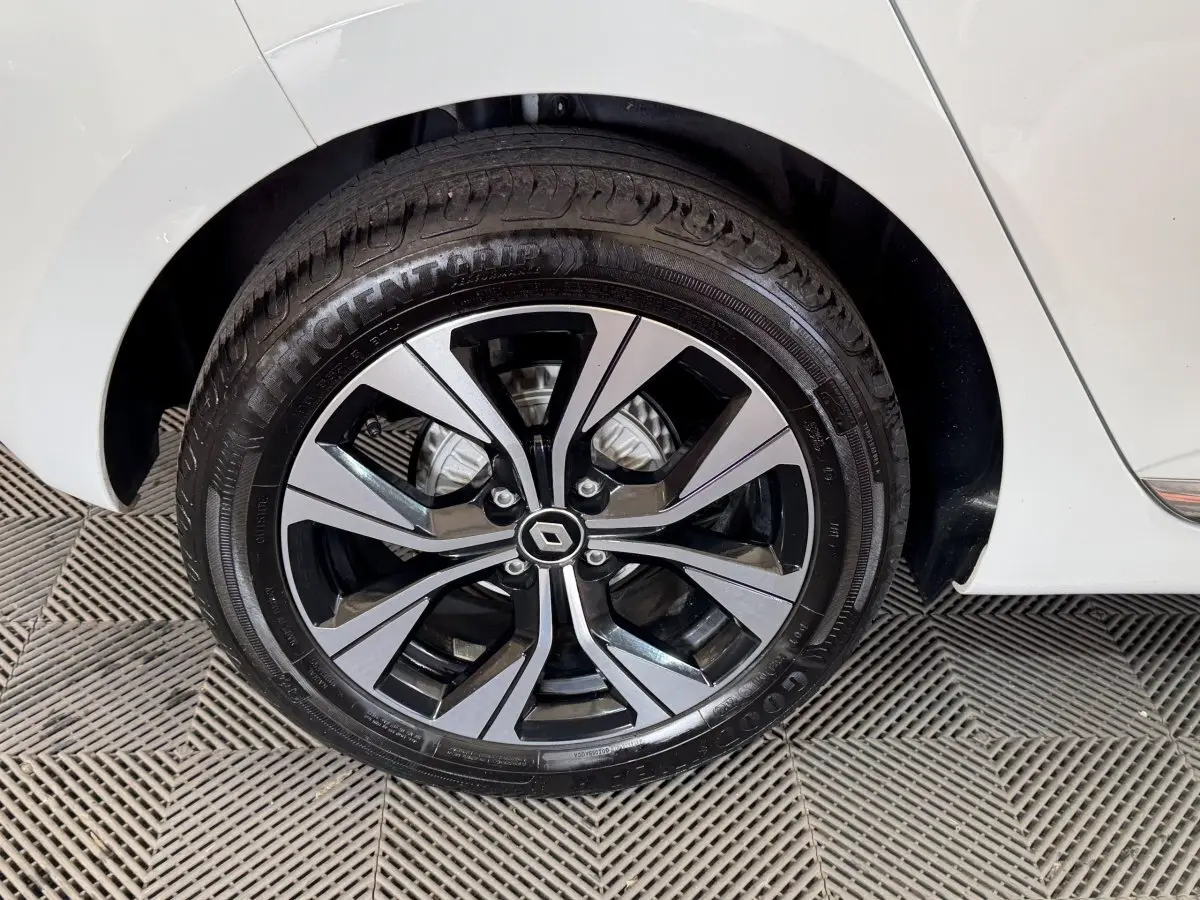 Gros plan sur la roue arrière droite blanche d’une Renault Clio 2023 avec jante alliage bicolore et logo Renault central.