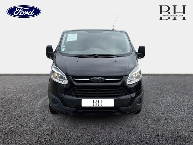 Vue avant d'un Ford Transit Custom Fourgon noir de 2013 avec calandre noire et phares halogènes allumés.