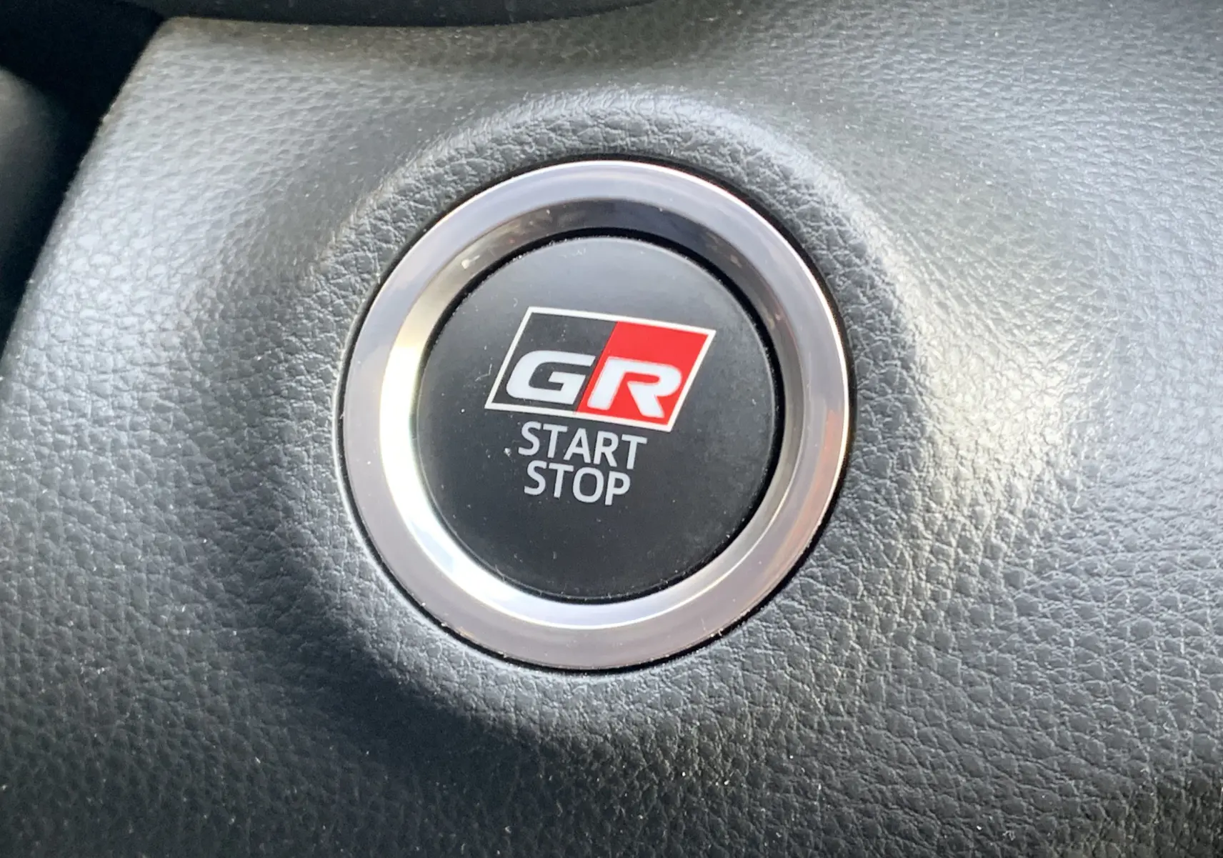 Bouton start-stop GR en gros plan sur le tableau de bord noir de la Toyota Yaris 1.6 VVT-I 261 Premium GR.