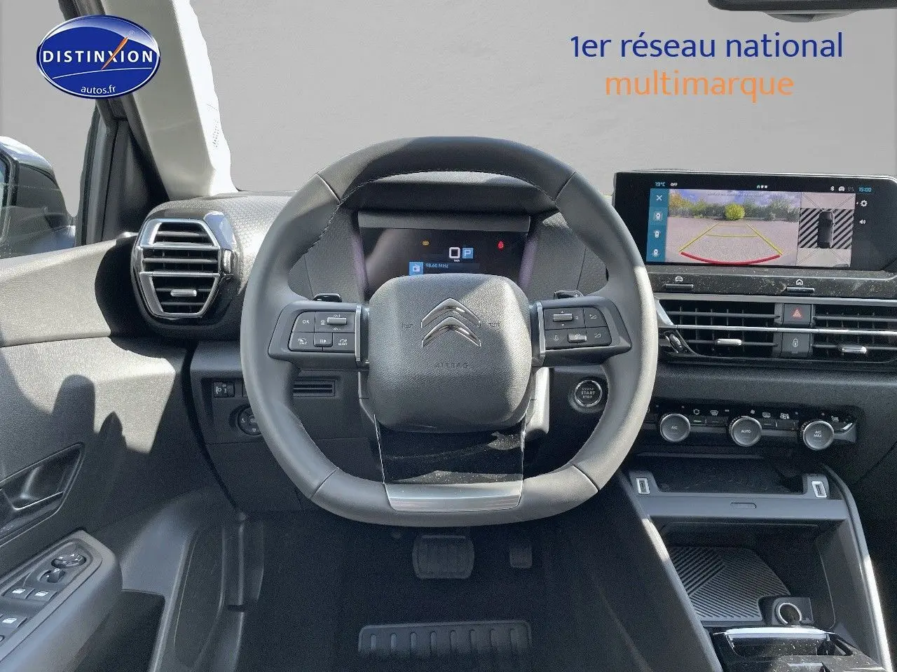 Vue intérieure centrée sur le volant et tableau de bord du Citroën C4 2024 avec écran multimédia et caméra de recul.