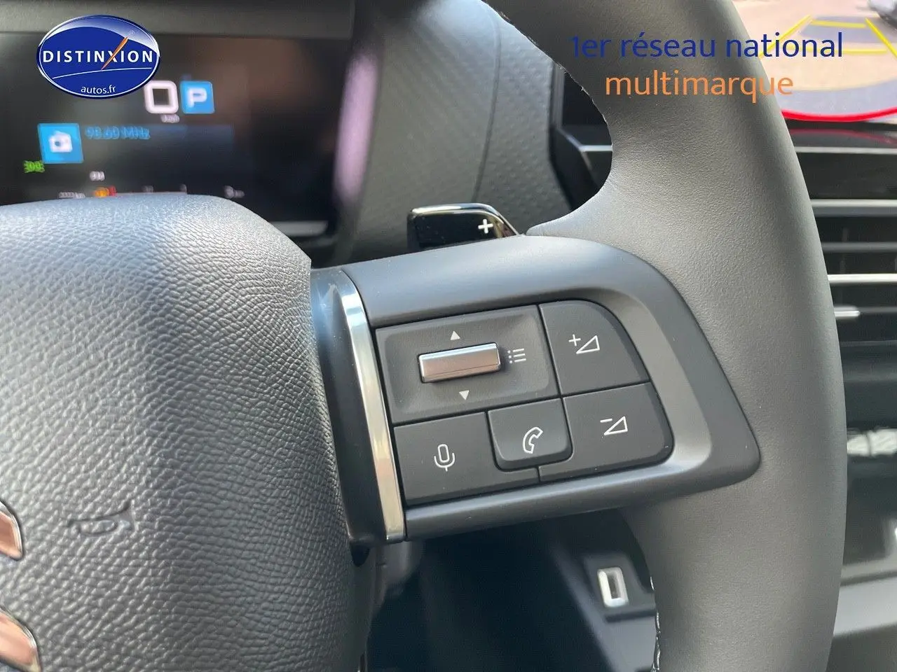 Gros plan sur les commandes au volant de la Citroën C4 2024 gris platinium, avec boutons de volume et téléphone.