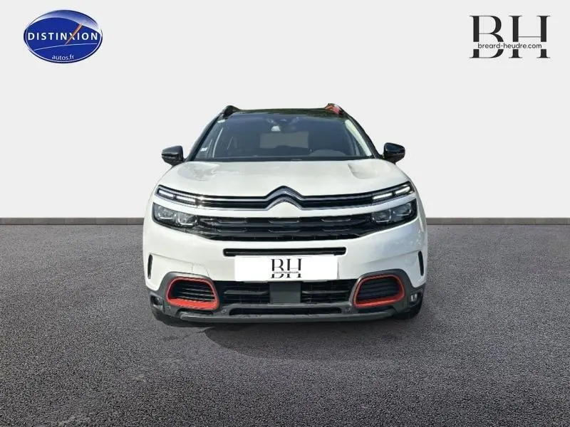 Vue avant d'un Citroën C5 Aircross blanc nacré avec détails rouges sur la calandre et toit noir.