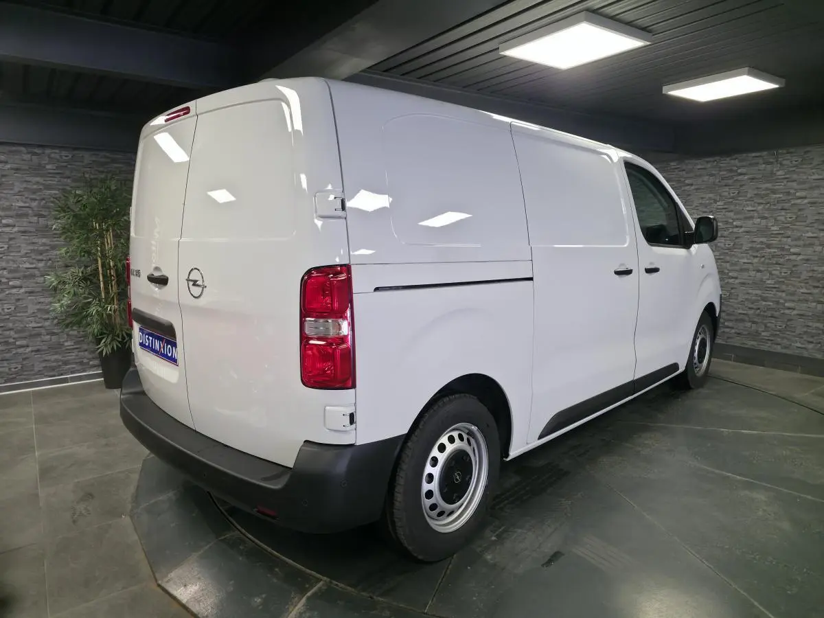 Vue 3/4 arrière droite d’un Opel Vivaro blanc, fourgon utilitaire avec portes arrière battantes et jantes tôles grises.