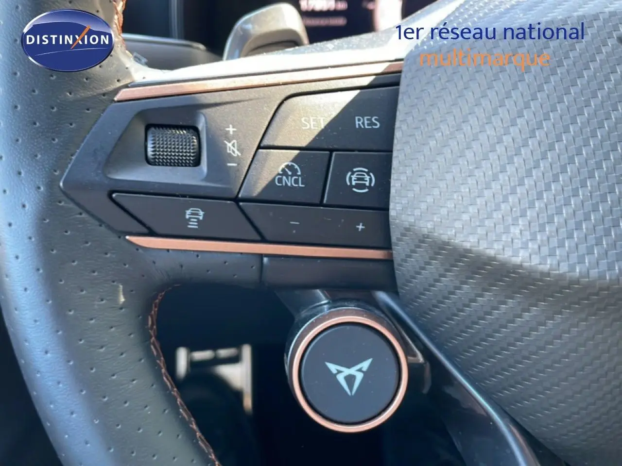 Gros plan sur le volant en cuir perforé du CUPRA Leon bleu Fjord, avec commandes multifonctions et logo CUPRA central.