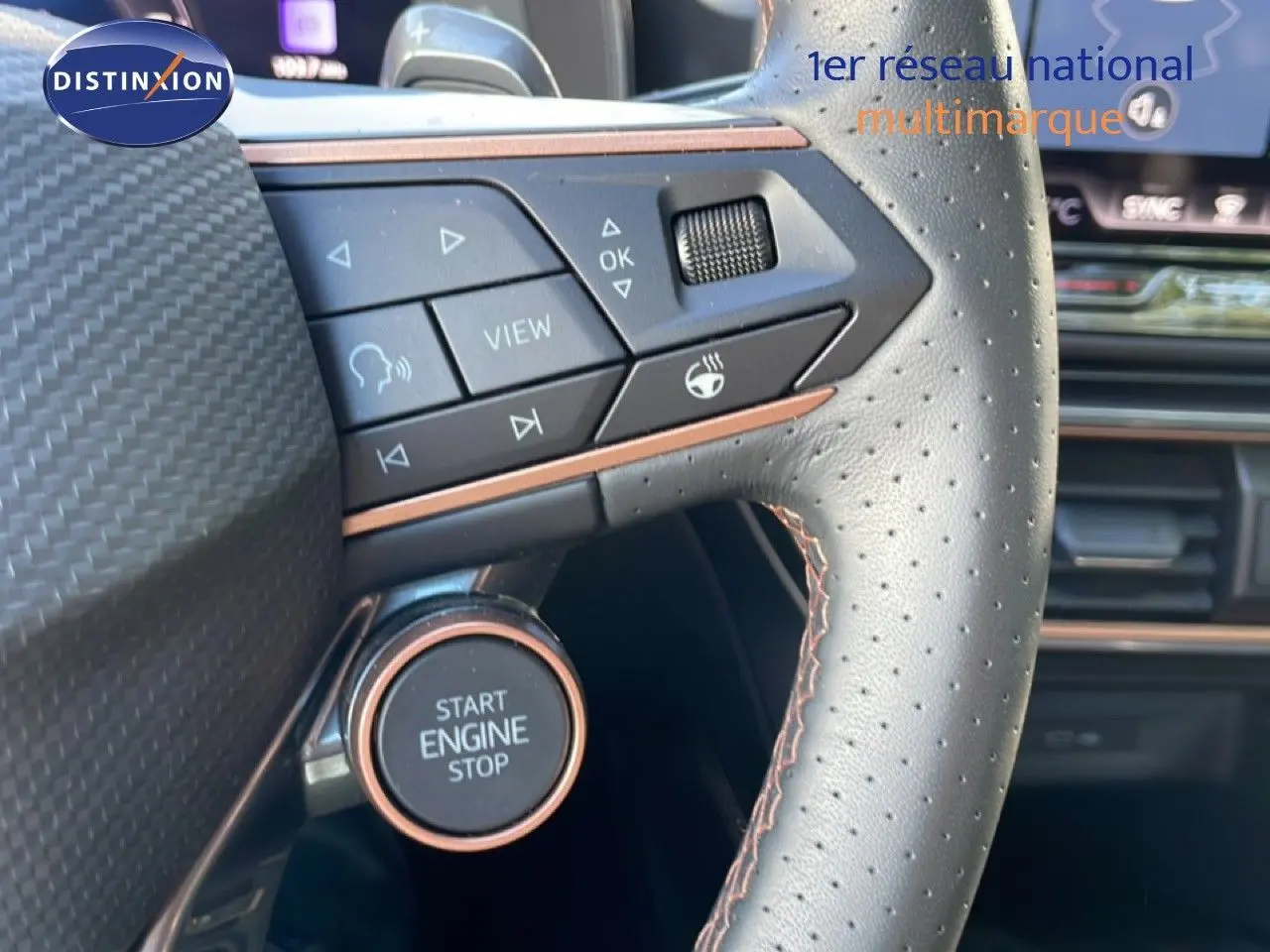 Gros plan sur le volant cuir perforé avec commandes intégrées et bouton start engine stop du CUPRA Leon bleu Fjord.