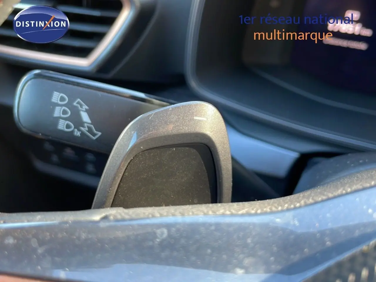 Détail du levier de commande des phares et palette de changement de vitesse dans l’habitacle d’une CUPRA Leon 1.5 eTSI bleu Fjord.