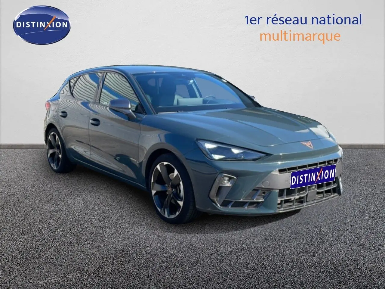Vue 3/4 avant d'une CUPRA Leon 1.5 eTSI 150CH DSG bleu Fjord avec jantes noires et détails sportifs.
