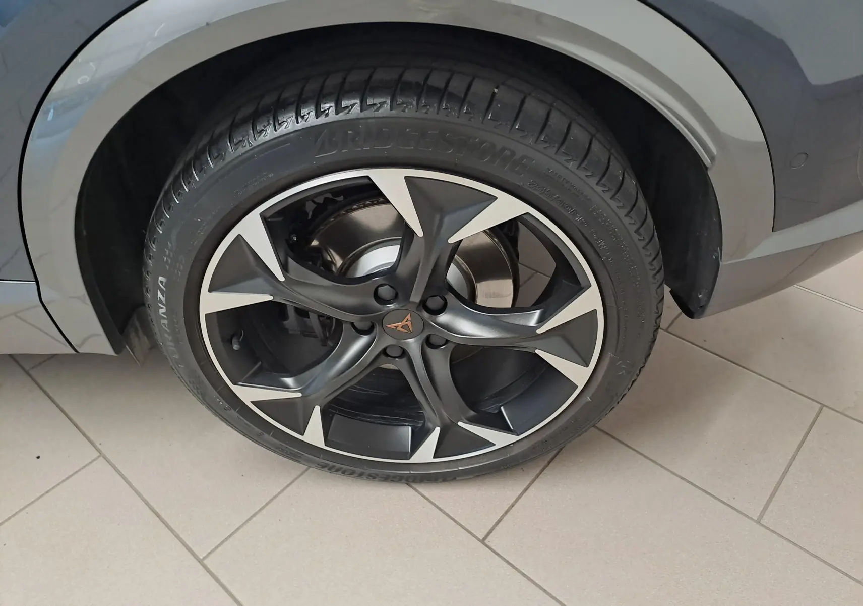 Gros plan sur la roue avant droite du CUPRA Formentor gris magnétique, avec jante noire et détails argentés.