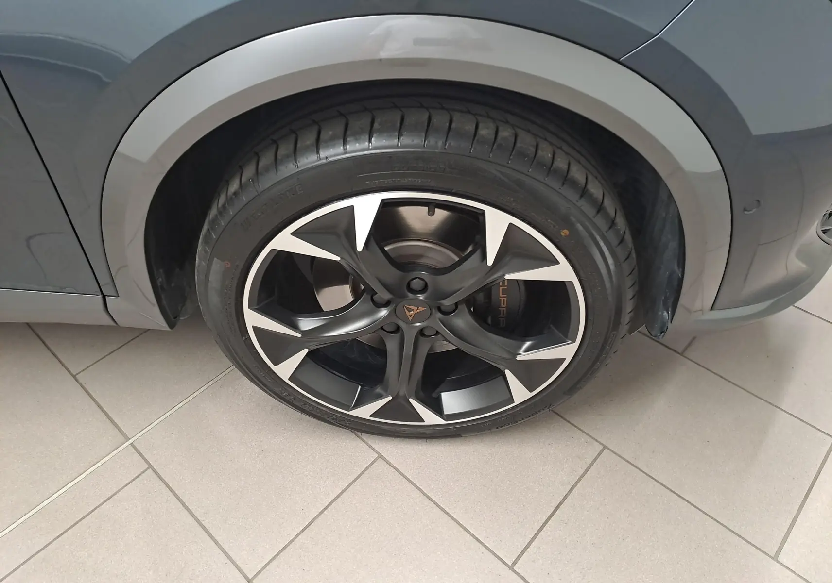Gros plan sur la roue avant droite du CUPRA Formentor 1.4 e-HYBRID 245 DSG6 VZ gris magnétique avec jante noire et argentée.
